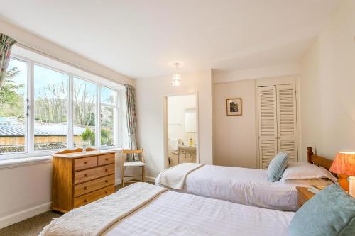 a bedroom with two beds and a window at April Cottage in Minehead