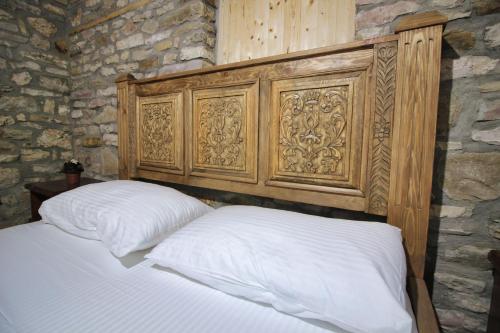 a bed with a wooden headboard in a room at Guri Guesthouse in Gjirokastër