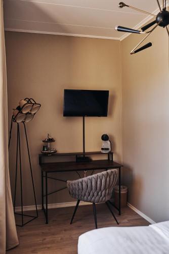 a bedroom with a desk with a television on a wall at Hotell Slottsgatan in Oskarshamn