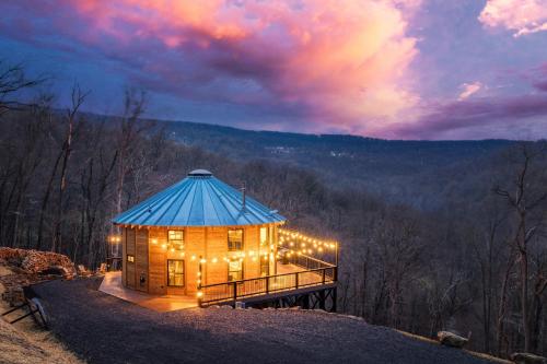 a large wooden building with a blue roof with lights at Skyline Yurt: Hot Tub~Wood Stove~WiFi~EVcharger in Front Royal