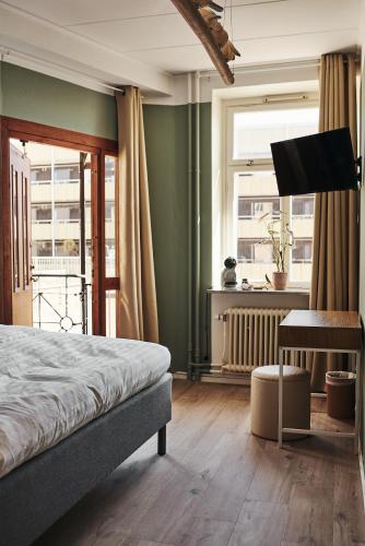 een slaapkamer met een bed, een bureau en ramen bij Hotell Slottsgatan in Oskarshamn