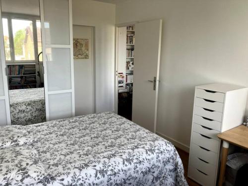 une chambre avec un lit et une commode dans l'établissement Charmant appartement au calme, à Villemomble
