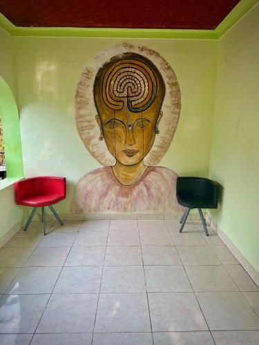 a mural of a head on a wall with two chairs at Rams Gratitude Inn in Varkala