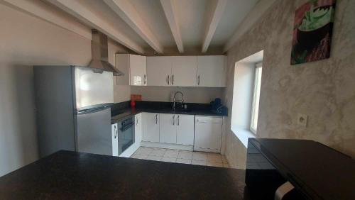 une cuisine avec des armoires blanches et un comptoir noir dans l'établissement Appartement à 2 pas du centre ville 6 personnes, au Puy-en-Velay