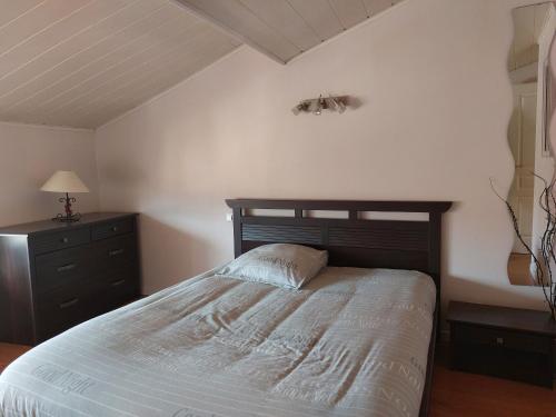 - une chambre avec un lit doté d'une tête de lit en bois et d'une commode dans l'établissement Appartement à 2 pas du centre ville 6 personnes, au Puy-en-Velay