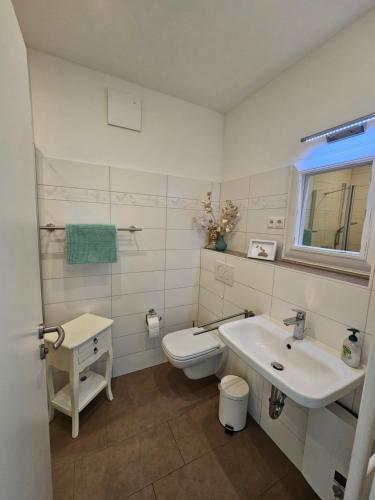 biała łazienka z toaletą i umywalką w obiekcie LeinenLos im Kajüting w mieście Dierhagen
