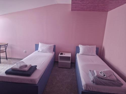 two beds in a room with pink walls and a table at Apartmani Maksa in Stanovo