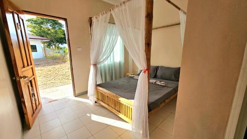a bedroom with a bed and a window with curtains at Mangoverde Guesthouse in Moalboal