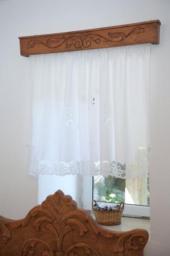 a window with a white curtain and a wooden bed at Guri Guesthouse in Gjirokastër