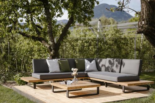 a couch and a coffee table on a wooden deck at Boutique Hotel Wiesenhof - Adults Only in Lana