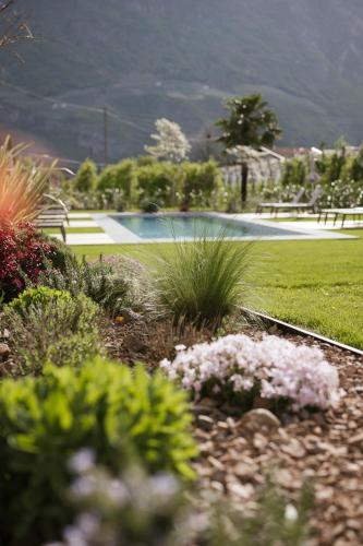 a garden with flowers and a pool in the background at Boutique Hotel Wiesenhof - Adults Only in Lana