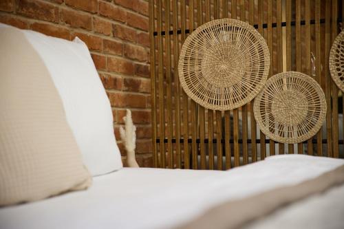 a bed with two rattan fans on a brick wall at IDEE Living: Modernes City-Apartment mit Altbaucharme in Weinheim