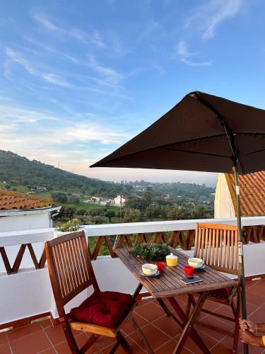 a table and chairs under an umbrella on a balcony at Casa da Boavista in Arraiolos