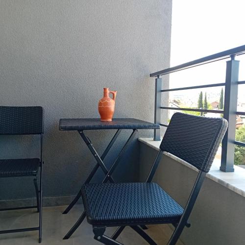 an orange vase sitting on a table next to two chairs at Apartment Kalin in Gevgelija