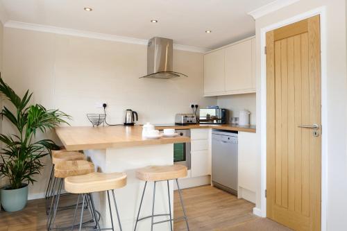 a kitchen with white cabinets and a counter with stools at Gwithian Holidays in Hayle