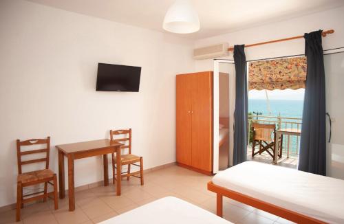 a room with a bed and a table and a balcony at Rosa's Beach Studios in Lourdhata