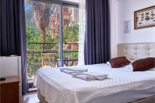 - une chambre avec un lit et une grande fenêtre dans l'établissement CARETTA PANSİYOn, à Kaş