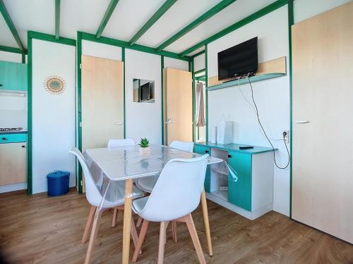 ein Esszimmer mit einem Tisch und weißen Stühlen in der Unterkunft chalet calme in Givrand