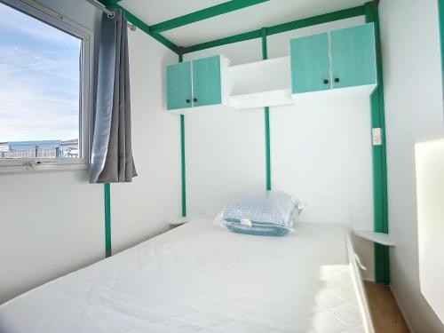 Schlafzimmer mit einem Bett mit blauen Schränken und einem Fenster in der Unterkunft chalet calme in Givrand