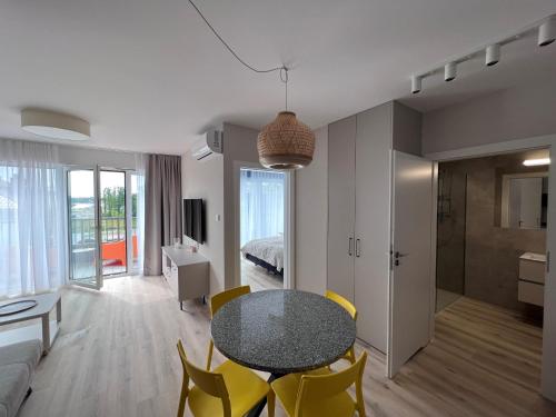 ein Wohnzimmer mit einem Tisch und gelben Stühlen in der Unterkunft Apartamenty MIW Dziwnów 21 in Dziwnów