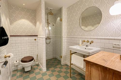 a bathroom with a sink toilet and a mirror at Stammershalle Badehotel in Bådsted