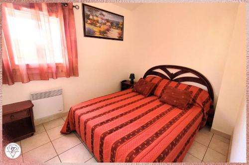une chambre avec un lit avec une couverture rouge et une fenêtre dans l'établissement La Palmeraie, maison 6pers en résidence avec piscine à 300m des plages de Valras-Plage, à Valras-Plage