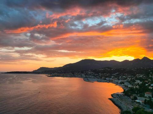 a sunset over a city and the water at Alloggio a picco sul mare in Grimaldi