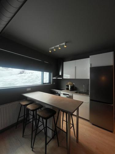 a kitchen with a table and stools and a refrigerator at LL Properties - L19 Elegant Lux in Akureyri