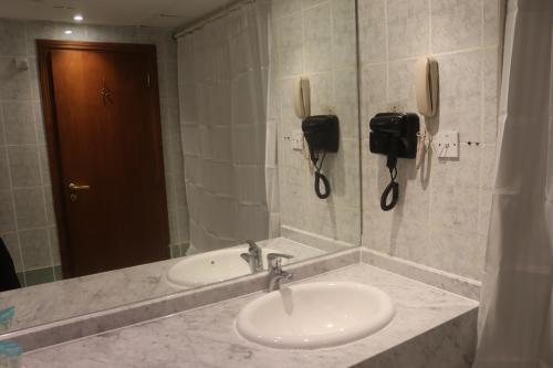 baño con lavabo, espejo y teléfono en GSS Avenue Hotel Ex Delmon Hotel, en Dubái