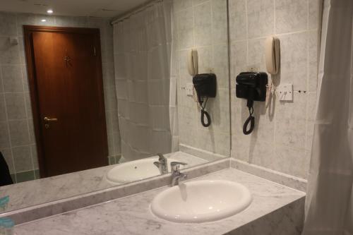 a bathroom with a sink and a mirror and a phone at GSS Avenue Hotel Ex Delmon Hotel in Dubai