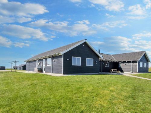 a black house with a grassy field in front of it at 22 person holiday home in Harbo re in Harboør