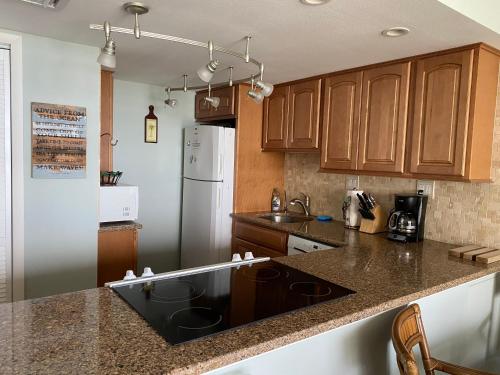 a kitchen with wooden cabinets and a black counter top at Pelican Condominium in New Smyrna Beach