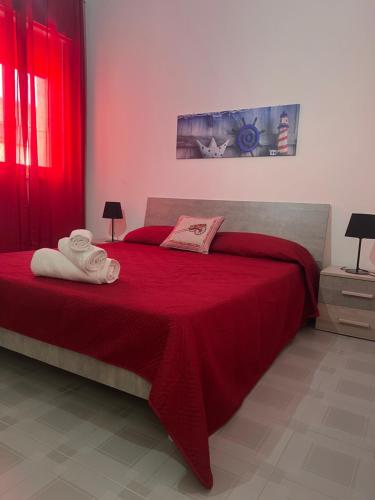 una camera da letto con un letto rosso con asciugamani sopra di Miramare a Balestrate