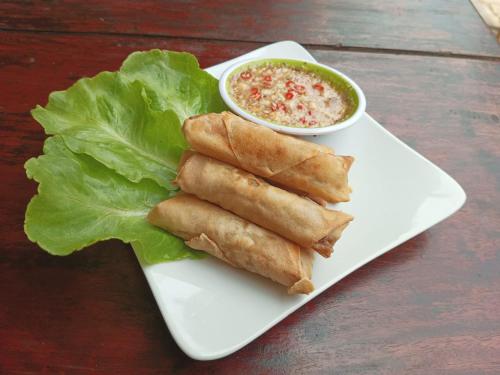 a plate of food with lettuce and a bowl of soup at Song Lao Guesthouse in Thakhek