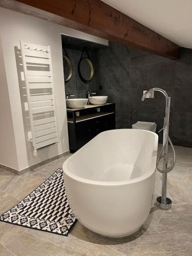La salle de bains est pourvue d'une grande baignoire blanche et de 2 lavabos. dans l'établissement Chalet de la buche croisée, à Combloux