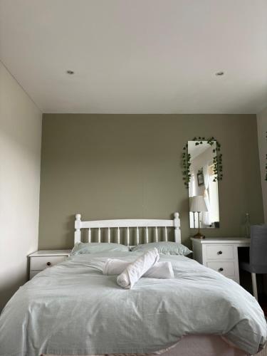 a bedroom with a white bed and a mirror at Aran Walkers Lodge in Inis Mor
