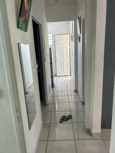 um corredor com um par de chinelos no chão em Maison tartanaise em La Trinité