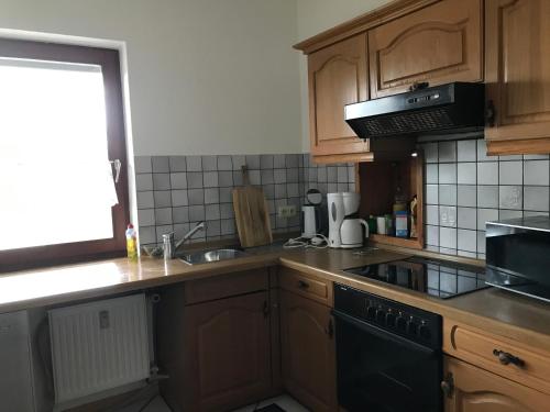 a kitchen with wooden cabinets and a black stove top oven at Ferienwohnung Landidylle in Friedrichshausen