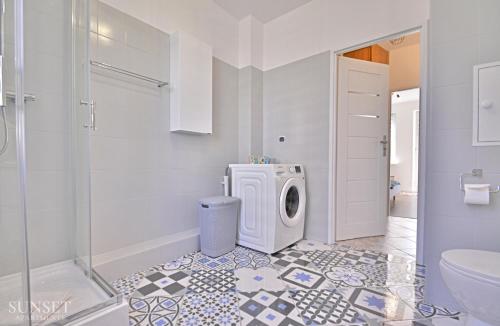 une salle de bain blanche avec une machine à laver à l'intérieur dans l'établissement Sunset Apartments - Monte Cassino 6 - przestronny apartament przy deptaku, à Świnoujście