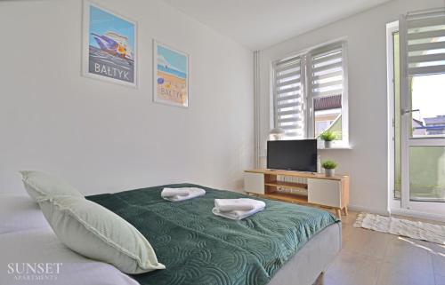Cette chambre blanche dispose d'un lit et d'une télévision. dans l'établissement Sunset Apartments - Monte Cassino 6 - przestronny apartament przy deptaku, à Świnoujście