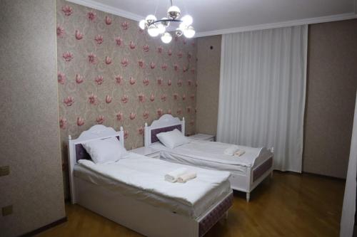 two beds in a hotel room with white sheets at Baku Red Villa in Baku