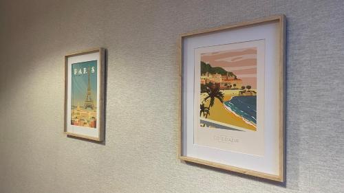 two framed pictures of the beach and the eiffel tower on a wall at Beautiful rooms in the center in Szczecin