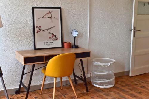 un escritorio con una silla amarilla junto a una pared en Appartement 3 pièces très lumineux, en Saint-Vallier