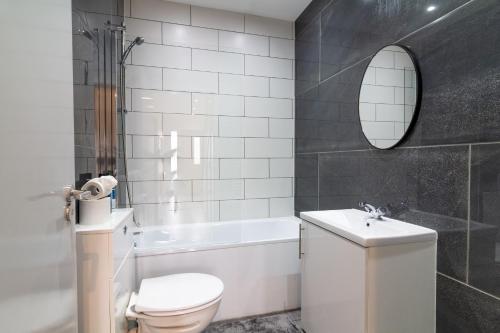 a bathroom with a toilet and a sink and a tub at Elegant Large Room in Beckenham