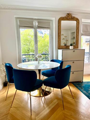 une salle à manger avec une table en verre et des chaises bleues dans l'établissement Studio près des Champs-Élysées, à Paris