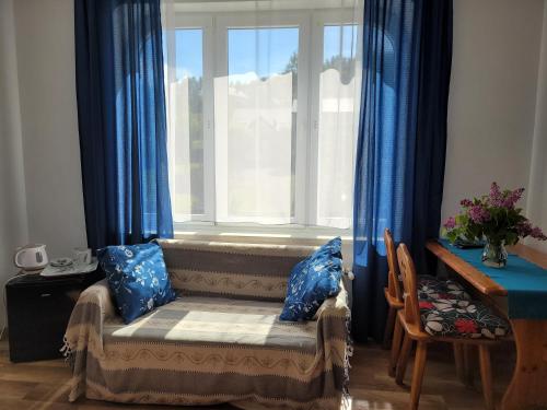a window seat in front of a window with blue curtains at Oberża Pod Kudłatym Aniołem in Cisna
