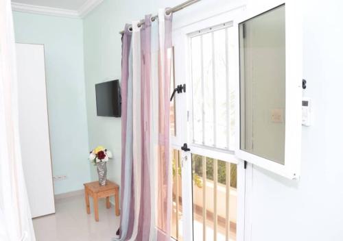 a white room with a window with pink curtains at Chez Ouly in Dakar