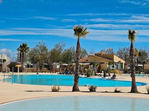 une piscine avec des palmiers dans un complexe hôtelier dans l'établissement Mobile Home de Valérie 