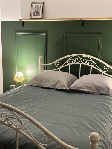 a bed with a green headboard and two pillows at T3 cosy vieux Laval in Laval