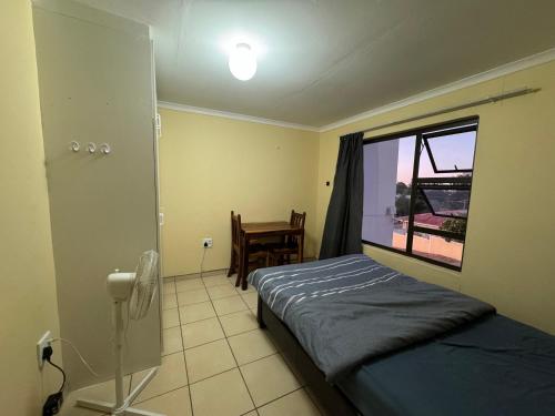 una camera con letto, finestra e tavolo di Ramblers Self-Catering Hostel (No Aircon/No TV/No Pool) a Windhoek